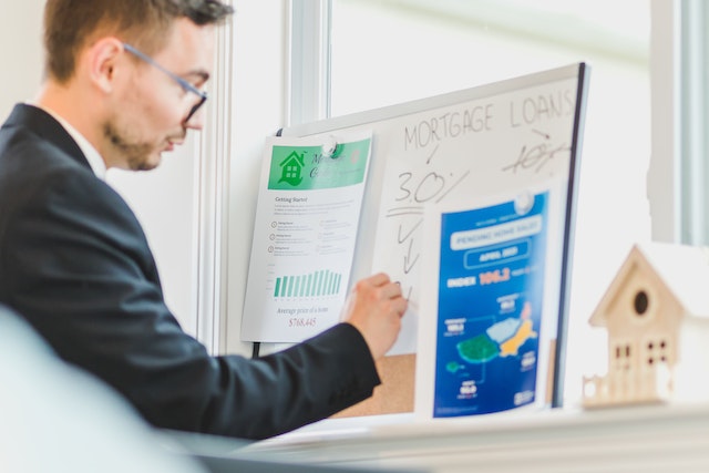 Person in a suit and glasses writing on a white board